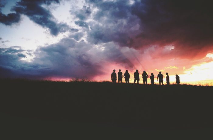 silhouette of nine persons standing on the hill