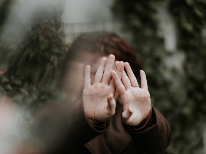 person in brown long sleeve shirt covering face with hand