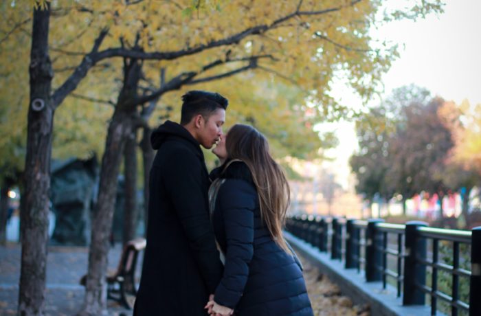 couple kissing in park under green leafed tree