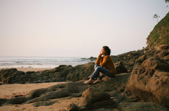 woman sitting near sea during daytime