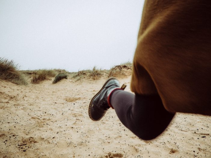 person walking on sandy ground