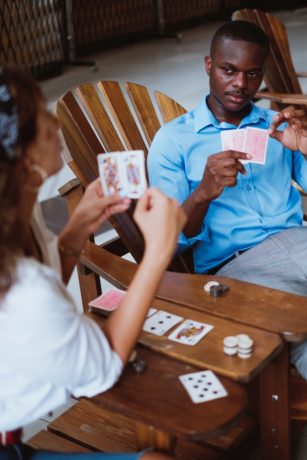 man in blue button up shirt holding playing cards